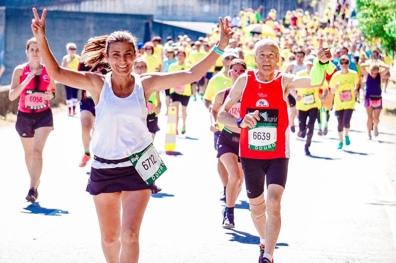 Two marathon runners smiling and waving in a crowd of runners